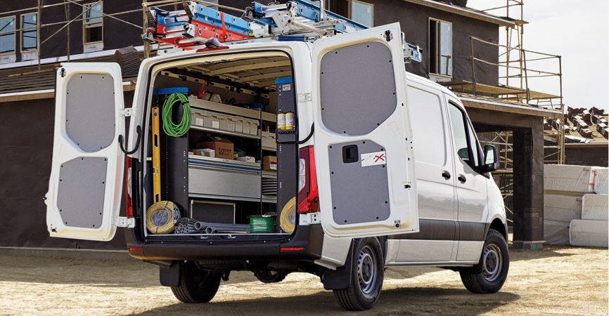 View of upfitted contractor van with back doors open at construction site.